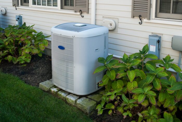 An air conditioner sitting outside near plants next to a home - OEG lawsuit, ontario energy group class action