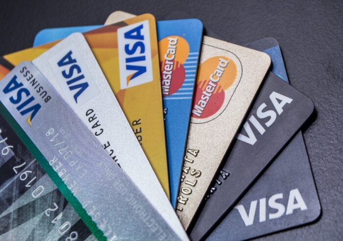 Visas and Mastercards fanned out on a black background - interchange fees settlement