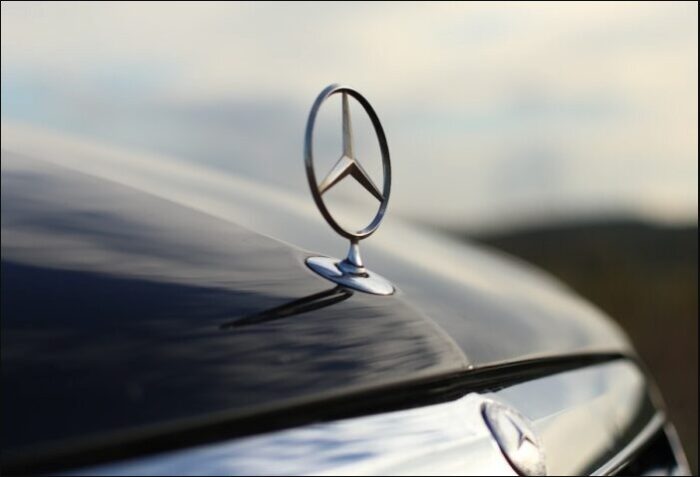Close up of Mercedes emblem against a cloudy sky.