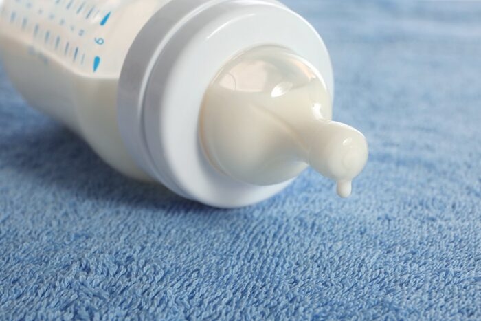 Baby bottle with milk on blue soft towel