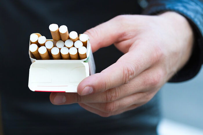 Close-up view of male hand holding a pack of cigarettes.
