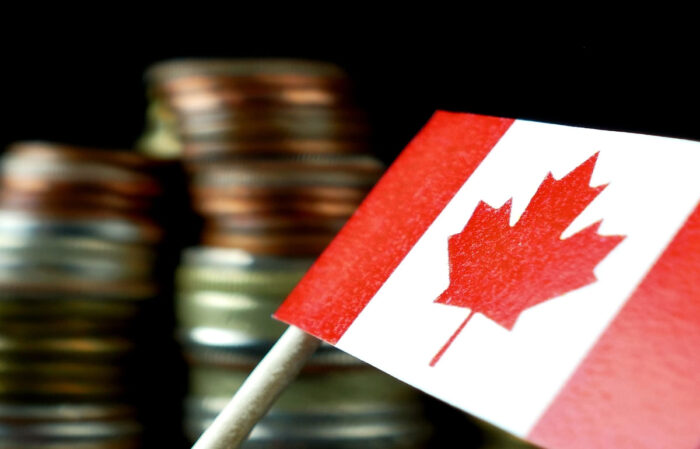 Canada flag waving with stack of money coins in the background.