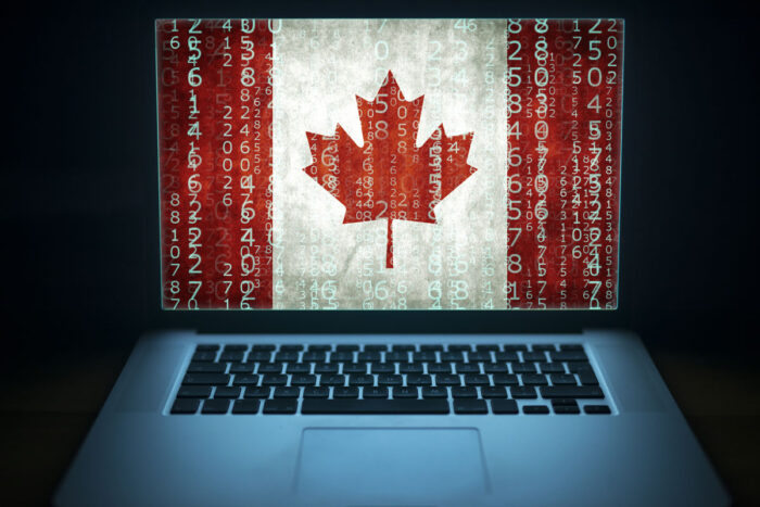 Laptop with binary computer code and Canada flag on the screen.