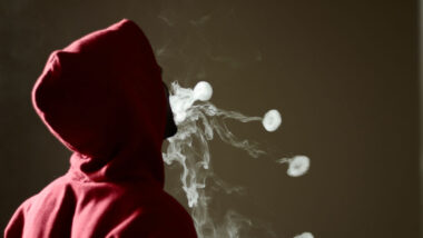 Young male in red hoodie vaping smoking.