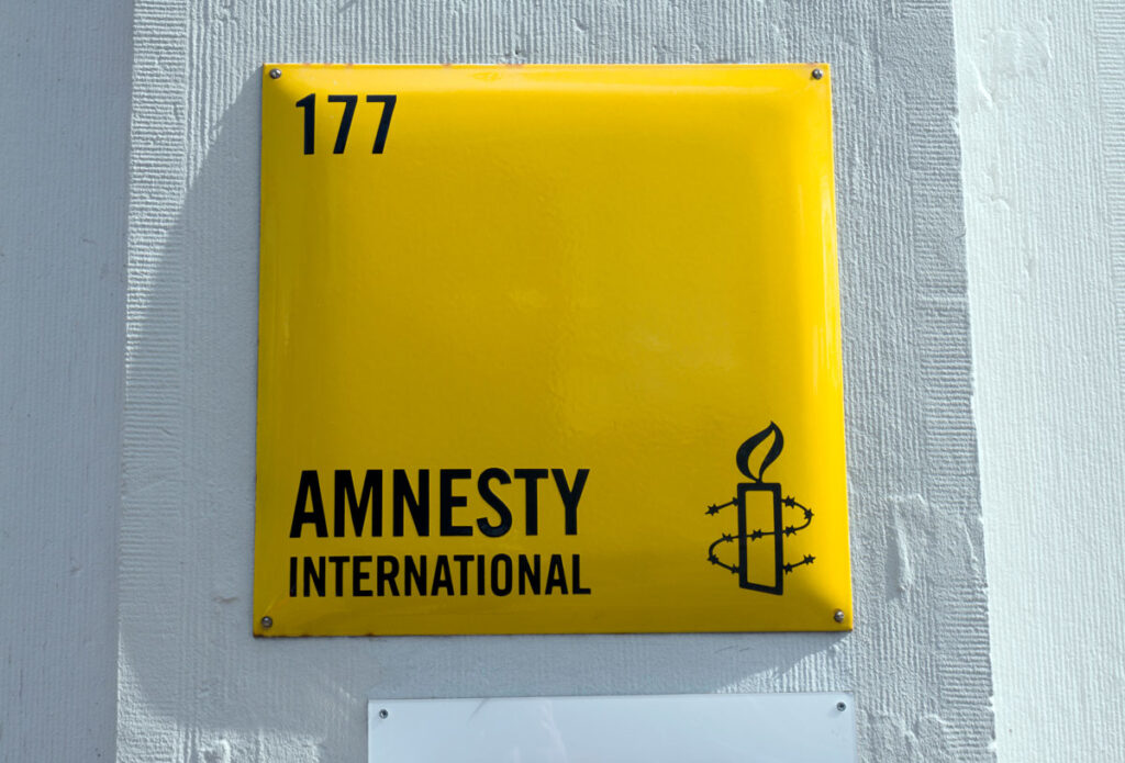 Close up of Amnesty International signage against a white wall.