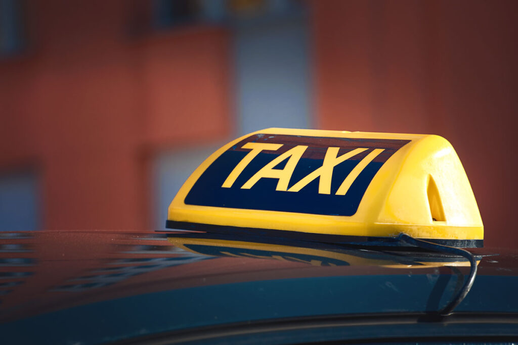 Close up of an illuminated Taxi sign on top of a cab.