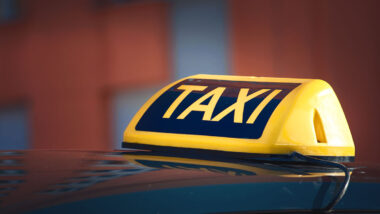 Close up of an illuminated Taxi sign on top of a cab.