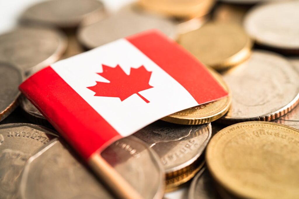 Mini Canadian flag resting on top of coins.