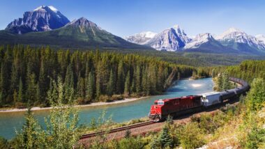 Train passing through Bow valley under the surveillance of mighty Rocky Mountains in Canada