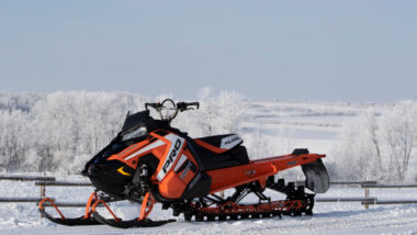 Polaris PRO800 RMK snowmobile. Sitting by a fence in a snow covered field, the long grass drenched in hoar frost.