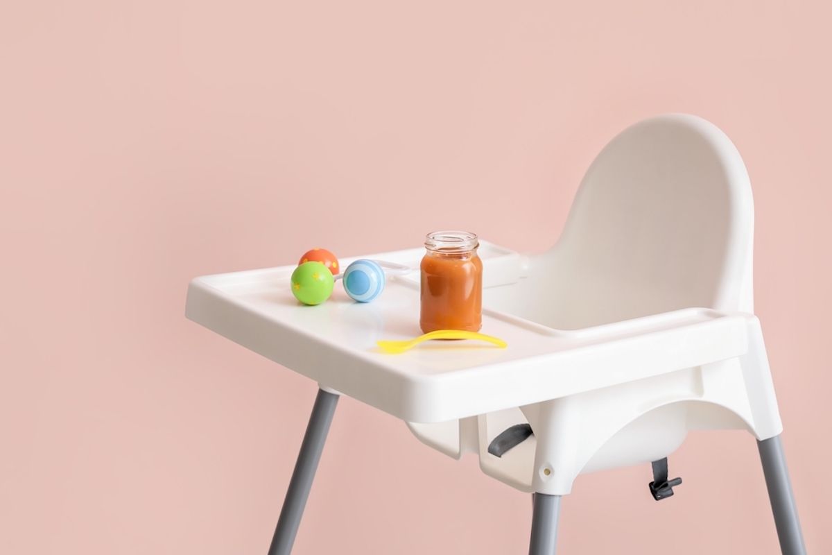 Baby highchair with food on color background representing the TOMY high chair recall.